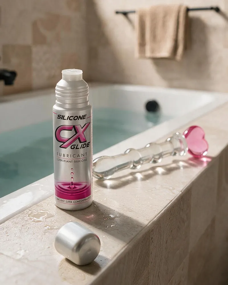 Lubrifiant silicone CX Glide avec un sextoy en verre au bord d’une baignoire