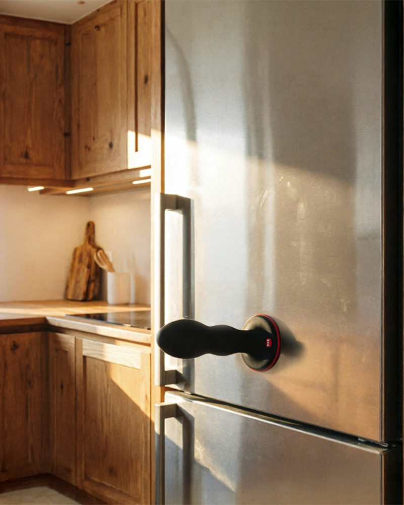 Gode ventouse noir fixé horizontalement sur la porte d’un réfrigérateur