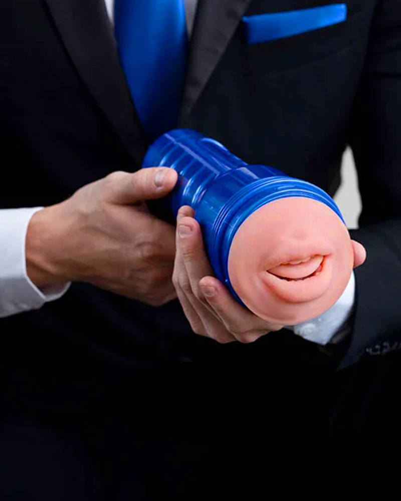 Homme en costume tenant un masturbateur Fleshlight Boost bleu avec une entrée réaliste en forme de bouche