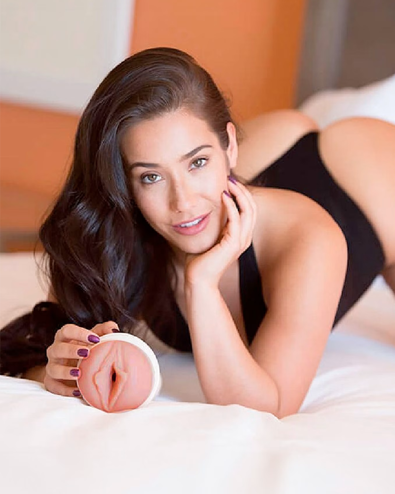 Femme allongée sur un lit tenant un masturbateur Fleshlight Girls avec une entrée anatomique réaliste